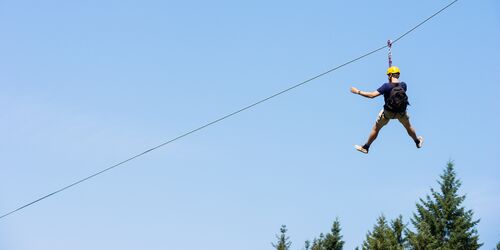 Mann beim Ziplining vor blauem Himmel