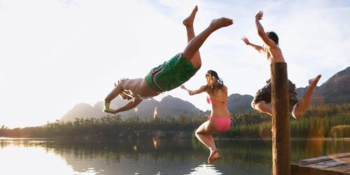 Junge Menschen, die von einem Steg in einen See springen