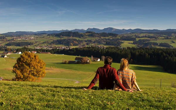 Mann und Frau auf grüner Wiese mit Blick auf Hügel