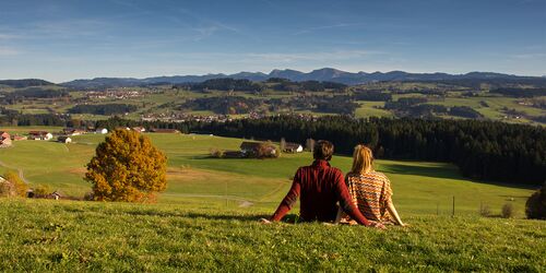 Mann und Frau auf grüner Wiese mit Blick auf Hügel