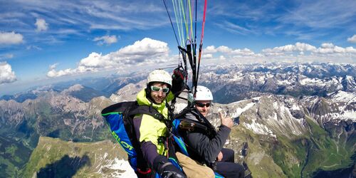 Zwei Männer beim Paragliding über den Alpen