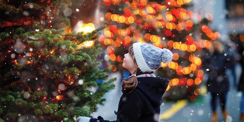 Kind vor Weihnachtsbaum auf Weihnachtsmarkt