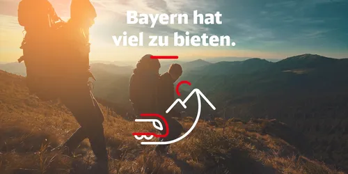 Menschen auf Berg bei Dämmerung mit Slogan "Bayern hat viel zu bieten"