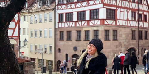 Frau in winterlicher Kleidung vor Fachwerkhaus