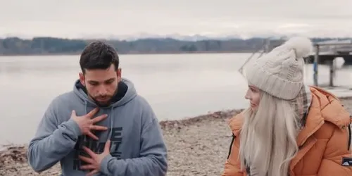 Zwei Personen sitzen am See auf dem Boden