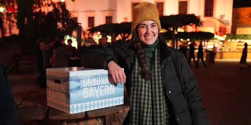 Lachende Frau lehnt sich an eine blaue Box 