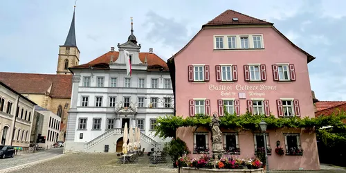 Foto Fußgängerzone mit Fokus auf dem, in rosa gehaltenen, Gasthof Goldene Krone und zwei weitere alte Gebäude