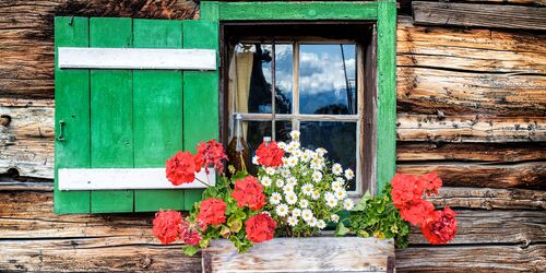 Fenster von Hütte mit Blumen davor