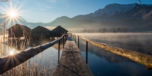 Steg im Kochelsee mit Sonnenschein und Nebel