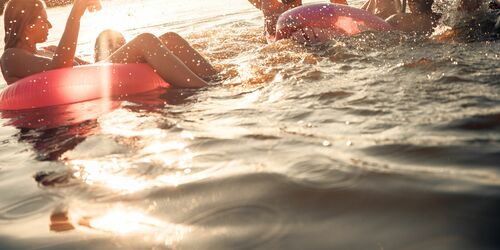 Junge Menschen beim Floaten auf See in der Dämmerung