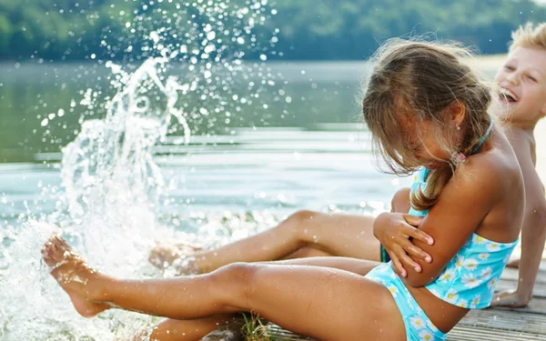 Junge und Mädchen auf Steg, die mit Wasser plantschen