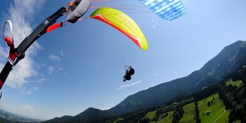 Person beim Gleitschirmfliegen mit Bergpanorama