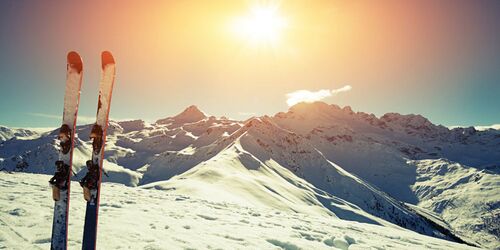 Bergpanorama bei Sonnenschein, zwei Skier in den Schnee gesteckt