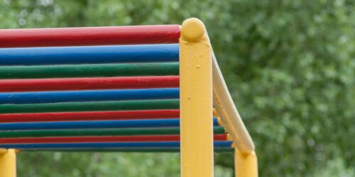 Buntes Klettergerüst mit Bäumen im Hintergrund