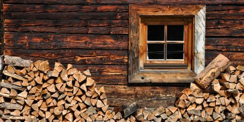 Blick auf Holzhütte mit Fenster und davor geschlagenem Holz