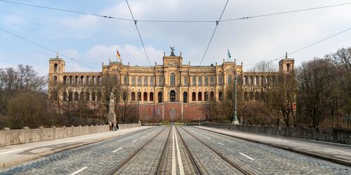 Eine Straße mit Tramlinie und Maximilianeum im Hintergrund