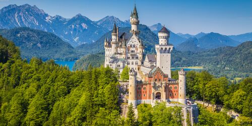 Grüne Wälder, Schloss Neuschwanstein, See und Berge bei blauem Himmel