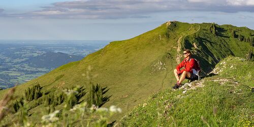 Frau sitzend auf grün bewachsenem Berg