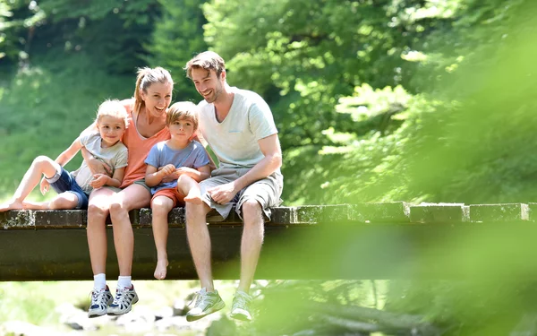 Junge Familie, die auf einem Steg sitzt